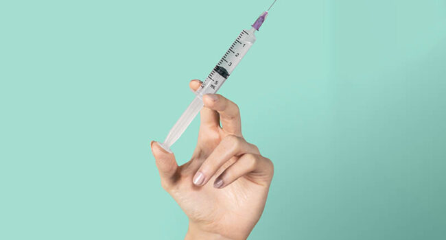 Feminine hand holding a syringe